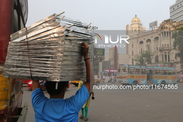 Indian daily laborers carry goods and cross a busy road in Kolkata, India, on October 17, 2024. 