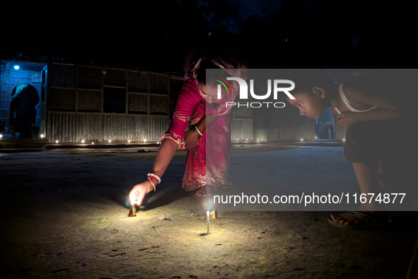 In Feni, Bangladesh, on October 17, 2024, a mother and child light oil lamps during the 'Deep Utsav or Light festival' before the Diwali fes...