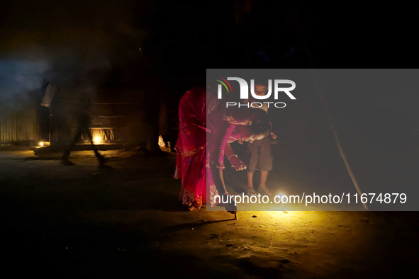 In Feni, Bangladesh, on October 17, 2024, a mother and child light oil lamps during the 'Deep Utsav or Light festival' before the Diwali fes...