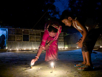 Mother and child play with light during the 'Deep Utsav or Light festival' before the Diwali festival in Feni, Bangladesh, on October 17, 20...