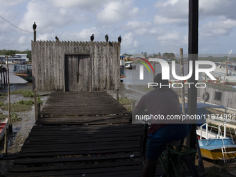 A man sits on a bicycle and looks out over the entrance to a pier in Afua, Para, Brazil, on September 29, 2024. (