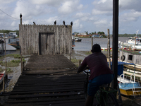 A man sits on a bicycle and looks out over the entrance to a pier in Afua, Para, Brazil, on September 29, 2024. (