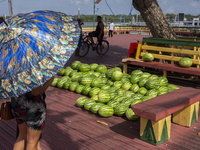 A woman with umbrellas looks at melons in the town's port in Afua, Para, Brazil, on September 29, 2024. (