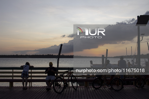 People and their bicycles watch the sunset on the banks of the Amazon River in Afua, Para, Brazil, on September 29, 2024. 