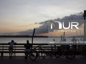 People and their bicycles watch the sunset on the banks of the Amazon River in Afua, Para, Brazil, on September 29, 2024. (