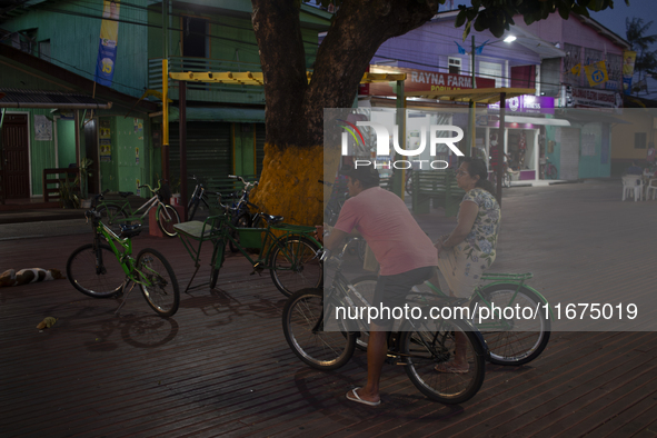 People and their bicycles are in the town square at night on the banks of the Amazon River in Afua, Para, Brazil, on September 29, 2024. 