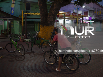 People and their bicycles are in the town square at night on the banks of the Amazon River in Afua, Para, Brazil, on September 29, 2024. (