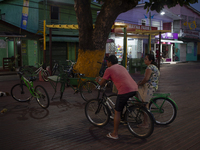 People and their bicycles are in the town square at night on the banks of the Amazon River in Afua, Para, Brazil, on September 29, 2024. (