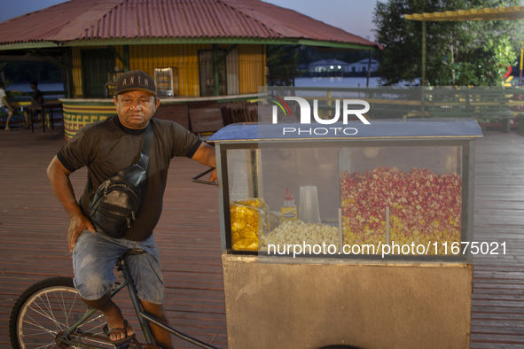 A popcorn vendor stands in the town square at night on the banks of the Amazon River in Afua, Para, Brazil, on September 29, 2024. 