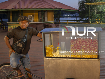 A popcorn vendor stands in the town square at night on the banks of the Amazon River in Afua, Para, Brazil, on September 29, 2024. (