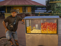 A popcorn vendor stands in the town square at night on the banks of the Amazon River in Afua, Para, Brazil, on September 29, 2024. (