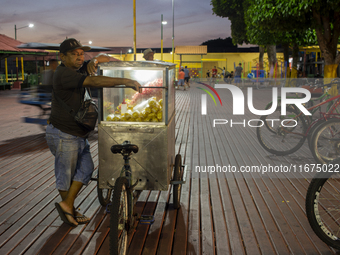 A popcorn vendor stands in the town square at night on the banks of the Amazon River in Afua, Para, Brazil, on September 29, 2024. (