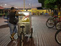 A popcorn vendor stands in the town square at night on the banks of the Amazon River in Afua, Para, Brazil, on September 29, 2024. (