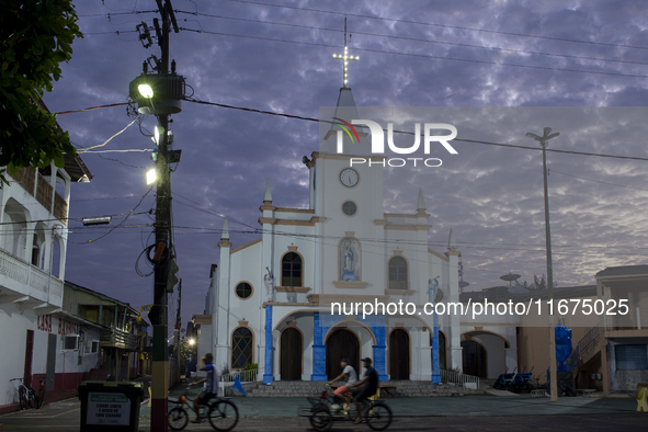 People ride bicycles at dawn with a church in the background in Afua, Para, Brazil, on September 30, 2024. 