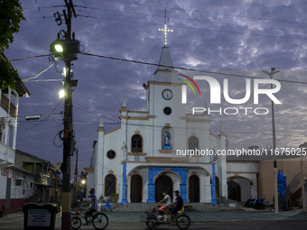 People ride bicycles at dawn with a church in the background in Afua, Para, Brazil, on September 30, 2024. (