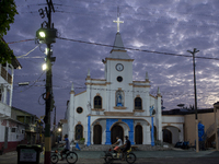 People ride bicycles at dawn with a church in the background in Afua, Para, Brazil, on September 30, 2024. (