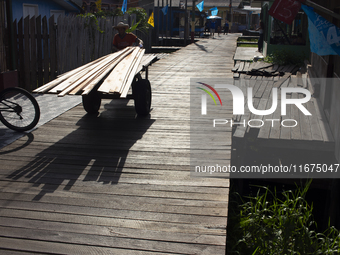 A man carries wood used to build the streets of the city of Afua in Afua, Para, Brazil, on October 1, 2024. (