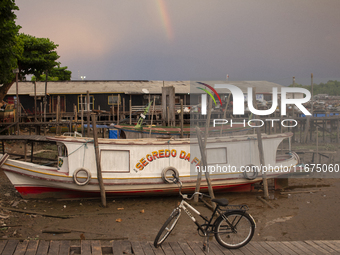 A boat and a bicycle appear at the mouth of the Amazon River with a rainbow in the background in Afua, Para, Brazil, on October 1, 2024. (