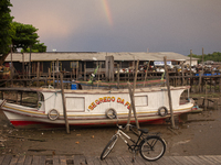 A boat and a bicycle appear at the mouth of the Amazon River with a rainbow in the background in Afua, Para, Brazil, on October 1, 2024. (