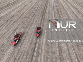 Workers drive a fertilizer spreader to distribute organic fertilizer in preparation for wheat planting in a high-standard farmland in Liaoch...