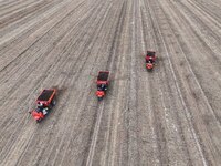 Workers drive a fertilizer spreader to distribute organic fertilizer in preparation for wheat planting in a high-standard farmland in Liaoch...