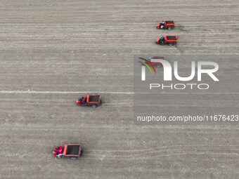 Workers drive a fertilizer spreader to distribute organic fertilizer in preparation for wheat planting in a high-standard farmland in Liaoch...