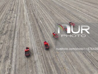 Workers drive a fertilizer spreader to distribute organic fertilizer in preparation for wheat planting in a high-standard farmland in Liaoch...