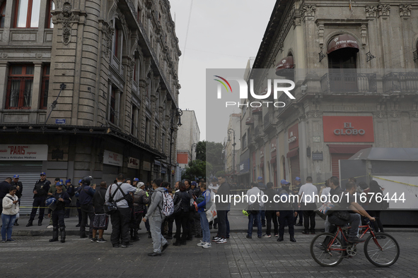 A group of passers-by watches a police operation after an attack on Diana Sanchez Barrios, leader of traders in the Historic Centre of Mexic...