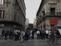 A group of passers-by watches a police operation after an attack on Diana Sanchez Barrios, leader of traders in the Historic Centre of Mexic...