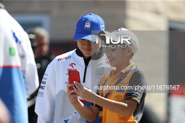 Yuki Tsunoda takes a photo with a young fan in the paddock at Circuit of the Americas in Austin, Texas, on October 17, 2024. 