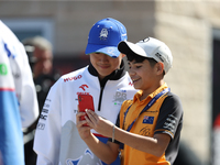 Yuki Tsunoda takes a photo with a young fan in the paddock at Circuit of the Americas in Austin, Texas, on October 17, 2024. (