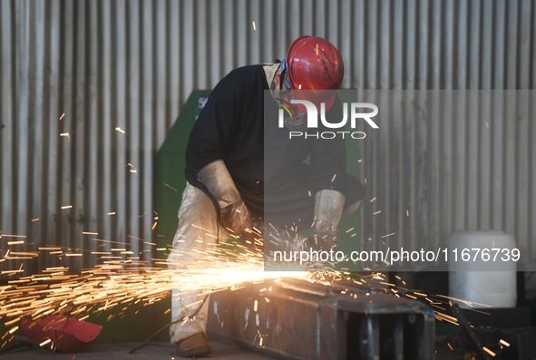 A worker polishes machinery parts for export at a machinery manufacturing workshop in Hangzhou, Zhejiang province, China, on October 18, 202...