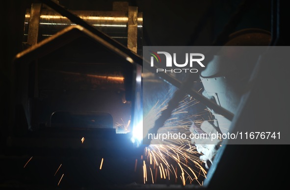 A worker welds machinery parts for export at a machinery manufacturing workshop in Hangzhou, Zhejiang province, China, on October 18, 2024....