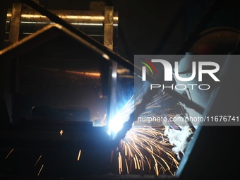 A worker welds machinery parts for export at a machinery manufacturing workshop in Hangzhou, Zhejiang province, China, on October 18, 2024....