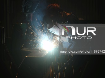 A worker welds machinery parts for export at a machinery manufacturing workshop in Hangzhou, Zhejiang province, China, on October 18, 2024....