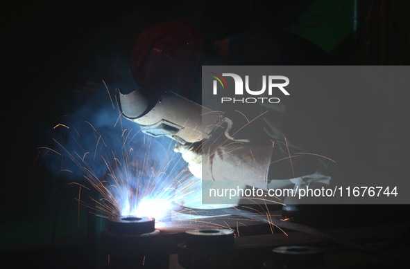 A worker welds machinery parts for export at a machinery manufacturing workshop in Hangzhou, Zhejiang province, China, on October 18, 2024....