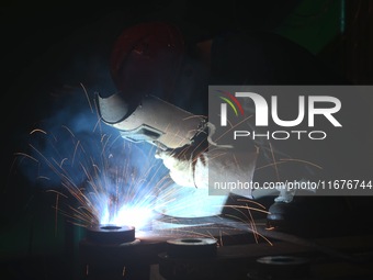 A worker welds machinery parts for export at a machinery manufacturing workshop in Hangzhou, Zhejiang province, China, on October 18, 2024....