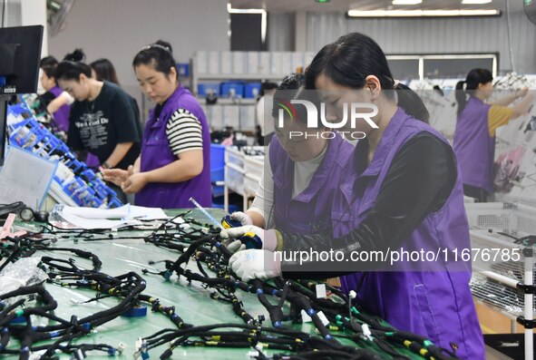 Workers rush to make products at an automobile wiring harness production line in Handan, China, on October 8, 2024. On October 8, 2024, the...