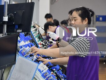 Workers rush to make products at an automobile wiring harness production line in Handan, China, on October 8, 2024. On October 8, 2024, the...