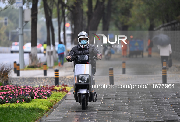 In Shenyang, China, on October 18, 2024, people change into thick clothes to travel after the rain. 