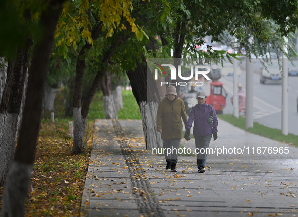 In Shenyang, China, on October 18, 2024, people change into thick clothes to travel after the rain. 