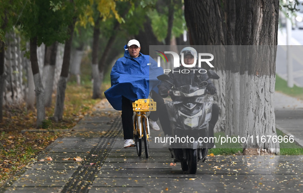 In Shenyang, China, on October 18, 2024, people change into thick clothes to travel after the rain. 