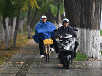 In Shenyang, China, on October 18, 2024, people change into thick clothes to travel after the rain. (