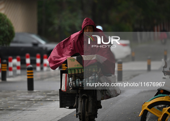 In Shenyang, China, on October 18, 2024, people change into thick clothes to travel after the rain. 