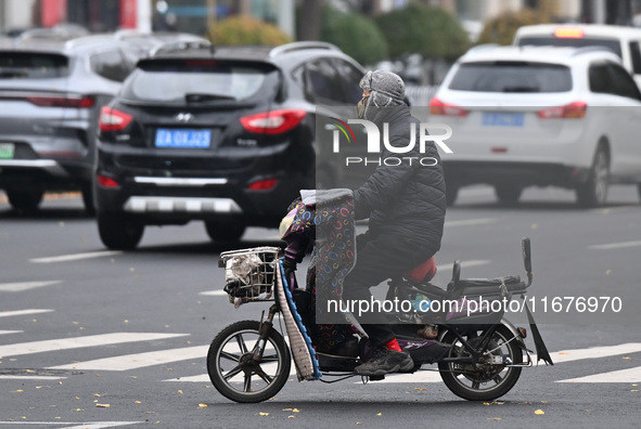 In Shenyang, China, on October 18, 2024, people change into thick clothes to travel after the rain. 