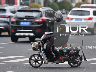 In Shenyang, China, on October 18, 2024, people change into thick clothes to travel after the rain. (