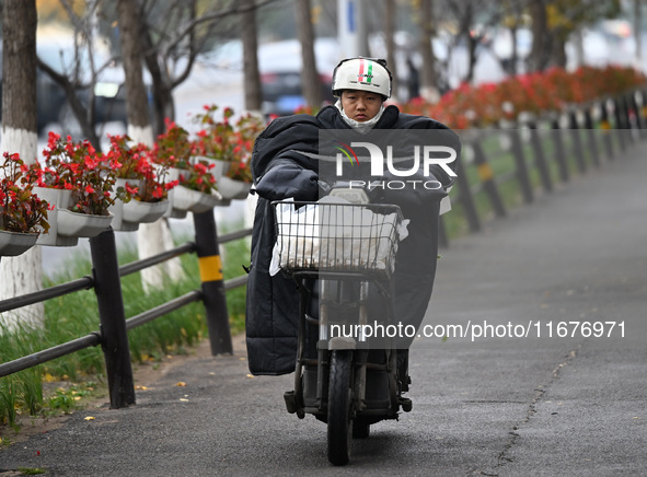 In Shenyang, China, on October 18, 2024, people change into thick clothes to travel after the rain. 