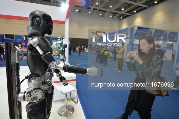 A visitor takes photos of a humanoid robot at the 2024 China International Consumer Electronics Expo in Qingdao, China, on October 18, 2024....