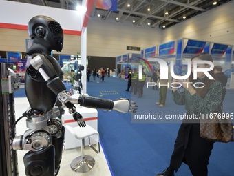 A visitor takes photos of a humanoid robot at the 2024 China International Consumer Electronics Expo in Qingdao, China, on October 18, 2024....