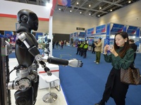 A visitor takes photos of a humanoid robot at the 2024 China International Consumer Electronics Expo in Qingdao, China, on October 18, 2024....